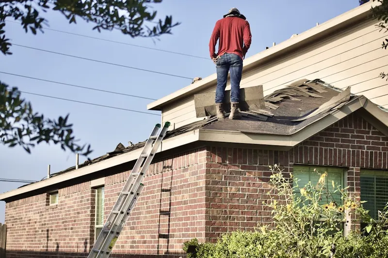 Professional roofer working on a residential roof in West Dennis